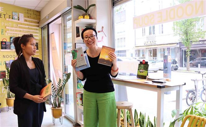 Nhà văn Như Quỳnh de Prelle giới thiệu những cuốn sách của mình đóng góp vào dự án “Tủ sách Việt trong nhà hàng Việt ở nước ngoài.” (Ảnh: Hương Giang/TTXVN) Tủ sách Việt trong nhà hàng Việt - Đưa sách Việt tới gần độc giả ảnh 4