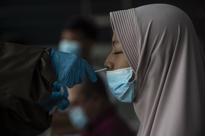 Nhân viên y tế lấy mẫu xét nghiệm COVID-19 cho người dân tại Nam Tangerang, Indonesia, ngày 20/5 vừa qua. (Ảnh: THX/TTXVN) Toàn thế giới ghi nhận 167.123.463 ca nhiễm SARS-CoV-2 ảnh 1
