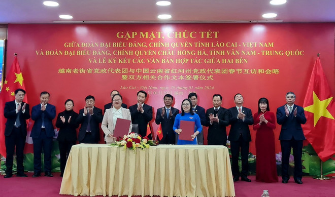 Lãnh đạo tỉnh Lào Cai và châu Hồng Hà chứng kiến các cơ quan chính quyền, đoàn thể, doanh nghiệp hai bên ký kết các biên bản thỏa thuận và ghi nhớ hợp tác. (Ảnh: Hương Thu/TTXVN) ttxvn_gap_mat_chuc_tet_giua_tinh_lao_cai_va_chau_hong_ha_trung_quoc.jpg