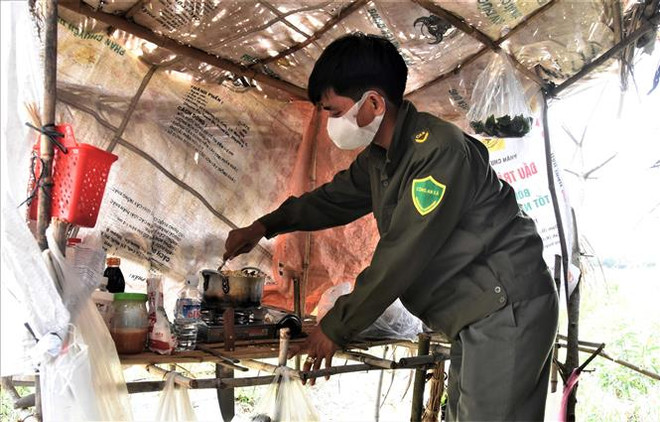 Công an viên Nguyễn Trường Duy chuẩn bị bữa trưa trong phần bếp sơ sài tại Chốt kiểm dịch 07, Đồn Biên phòng Cửa khẩu Quốc tế Mộc Bài, Tây Ninh. (Ảnh: Xuân Khu/TTXVN) Những ''lá chắn'' dịch COVID-19 nơi lối mòn biên giới Tây Nam ảnh 1