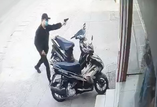 Tên cướp dùng súng uy hiếp nhân viên, người dân và bảo vệ. (Nguồn: Ảnh cắt từ clip) Đồng Nai: Truy bắt nam thanh niên xông vào ngân hàng cướp tiền ảnh 1