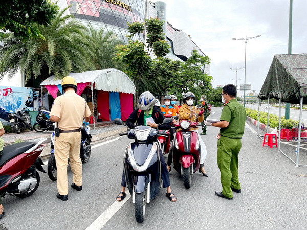 Lực lượng Công an tại chốt kiểm trên đường Phạm Văn Đồng, phường Hiệp Bình Chánh, Thủ Đức, kiểm tra giấy tờ của người lưu thông. (Ảnh: Thành Chung/TTXVN) Công an TP.HCM: Không có chuyện cấp giấy đi đường cho người F0 ảnh 1