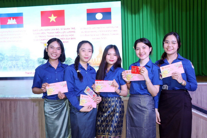 Du học sinh Lào vui vẻ với phong bào lì xì đón Tết được nhận tại chương trình giao lưu. (Ảnh: Xuân Khu/TTXVN) ttxvn_tang_cuong_giao_luu_van_hoa_that_chat_tinh_huu_nghi_giua_tuoi_tre_viet_nam-_lao-_campuchia.jpg