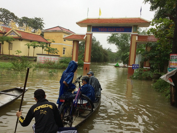 Người dân ở xã Quảng Thọ, huyện Quảng Điền đi lại bằng thuyền. (Ảnh: Hồ Cầu/TTXVN) Mưa to, các hồ thủy điện ở Thừa Thiên-Huế xả lũ gây úng ngập cục bộ ảnh 1