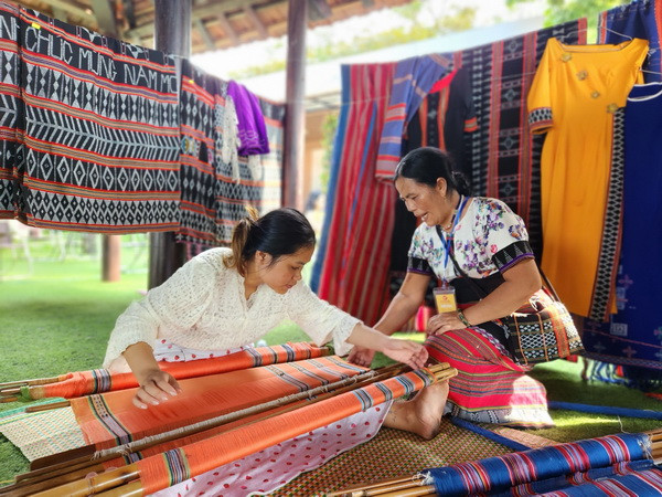 Các nghệ nhân trình diễn kỹ thuật tinh xảo dệt lụa và thổ cẩm truyền thống. (Ảnh: Tường Vi/TTXVN) Thừa Thiên-Huế: Tôn vinh tinh hoa các làng nghề truyền thống Việt Nam ảnh 1