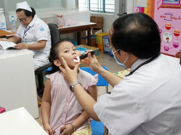 Bác sỹ Bệnh viện Nhi đồng 1 Thành phố Hồ Chí Minh thăm khám cho trẻ. (Ảnh: Phương Vy/TTXVN) Côn trùng bay vào miệng trẻ - Mối nguy khi xử lý không đúng cách ảnh 1