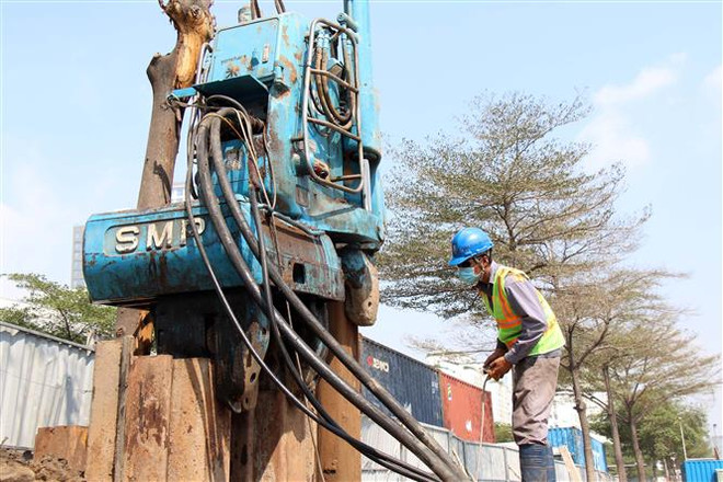 Công nhân điều khiển thiết bị thi công tại Dự án hầm chui nút giao thông Nguyễn Văn Linh-Nguyễn Hữu Thọ. (Ảnh: Tiến Lực/TTXVN) Trên những công trường dự án giao thông thi công xuyên Tết ảnh 2