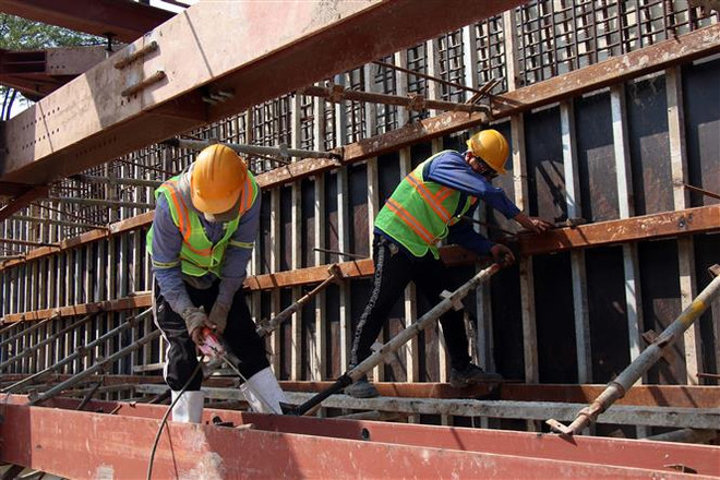 Công nhân thi công trên công trường Dự án hầm chui nút giao thông Nguyễn Văn Linh-Nguyễn Hữu Thọ (Quận 7, Thành phố Hồ Chí Minh). (Ảnh: Tiến Lực/TTXVN) Trên những công trường dự án giao thông thi công xuyên Tết ảnh 1