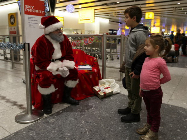 Ông già Noel với hành khách nhí trong chương trình đón Giáng sinh của Vietnam Airlines tại sân bay Heathrow (Anh). (Ảnh Lê Phương/Vietnam+) Hãng hàng không Vietnam Airlines lớn mạnh tại thị trường Anh ảnh 1