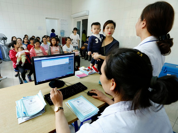 Nhân viên y tế làm thủ tục tiêm chủng cho trẻ tại Trung tâm Y tế Dự phòng Hà Nội. (Ảnh: Dương Ngọc/TTXVN) Hà Nội triển khai phần mềm quản lý thông tin tiêm chủng từ 1/4 ảnh 1