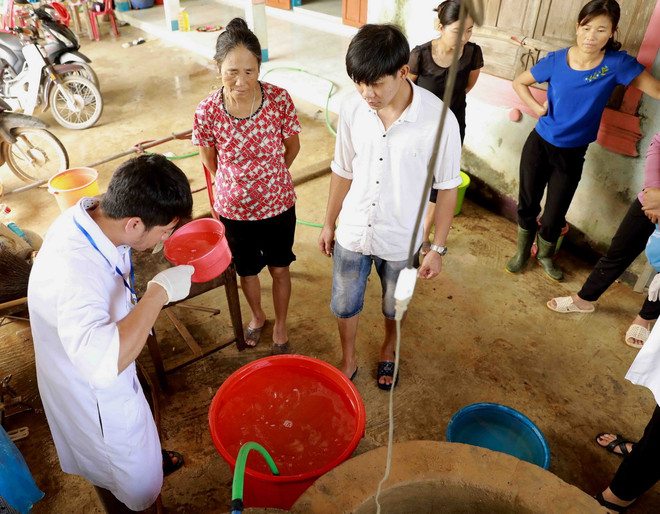 Nhân viên y tế dự phòng hướng dẫn người dân khử khuẩn nước sinh hoạt bằng dung dịch Cloramin B. (Ảnh: Vũ Sinh/TTXVN) ttxvn_xu ly nguon nuoc (2).jpg