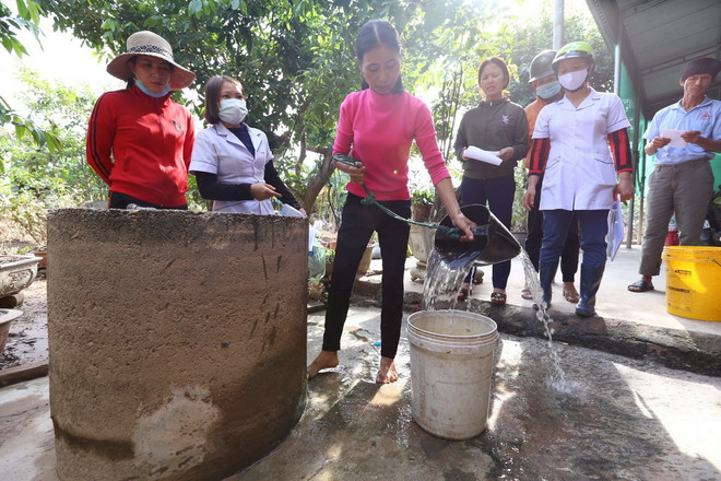 Nhân viên y tế hướng dẫn xử lý nước sinh hoạt an toàn cho người dân có giếng khơi bị ngập khi nước lũ dân cao. (Ảnh: Minh Quyết/TTXVN) ttxvn_xu ly nguon nuoc (1).jpeg