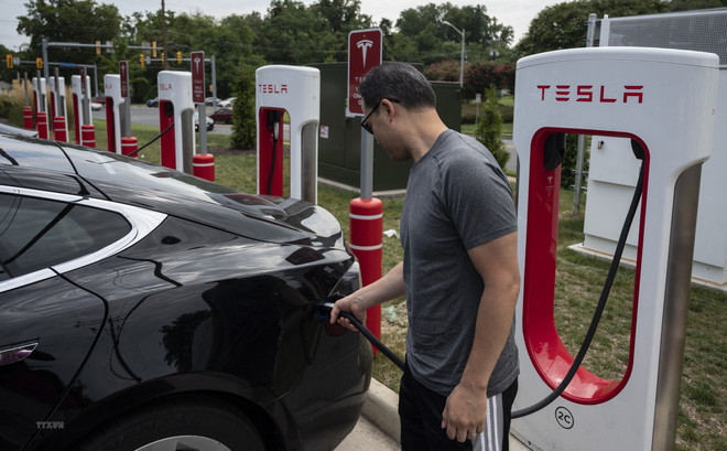 Người dân sạc điện cho ôtô tại một trạm sạc của Tesla ở Arlington, Virginia, Mỹ. (Ảnh: AFP/TTXVN) Thị trường EV của Mỹ chật vật với việc giảm giá và hàng tồn kho tăng ảnh 1