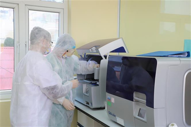 Nhân viên y tế xét nghiệm mẫu bệnh phẩm tại Trung tâm Kiểm soát bệnh tật (CDC) Quảng Ninh. (Ảnh: TTXVN phát) Quảng Ninh bác thông tin mua máy xét nghiệm COVID-19 cao gấp nhiều lần ảnh 1