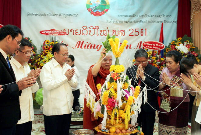 Ông Tất Thành Cang (thứ 3 từ trái sang) tham gia lễ "buộc chỉ cổ tay" cầu phúc trong năm mới truyền thống của Lào. (Ảnh: Xuân Khu/TTXVN) Lãnh đạo Thành phố Hồ Chí Minh chúc Tết cổ truyền Bunpimay của Lào ảnh 1
