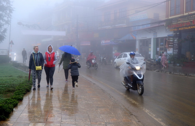 Du khách nước ngoài du lịch Sa Pa trong sương mù và giá lạnh. (Ảnh: Quốc Khánh/TTXVN) Rét hại bao phủ trên diện rộng các vùng núi cao ở Lào Cai ảnh 3