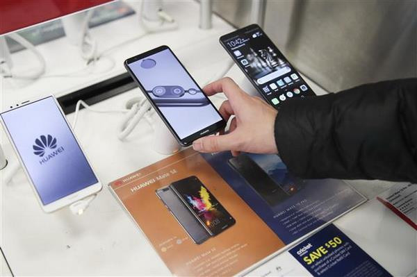 Khách hàng tìm hiểu về điện thoại thông minh của Tập đoàn công nghệ viễn thông Huawei tại một cửa hàng ở New York, Mỹ. (Nguồn: THX/TTXVN) Các công ty công nghệ Mỹ ''lách luật'' để tiếp tục làm ăn với Huawei ảnh 1