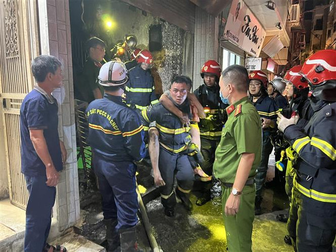 Lực lượng Cảnh sát PCCC và cứu nạn cứu hộ đưa người bị nạn ra khỏi đám cháy. (Ảnh TTXVN phát) Hà Nội: Cứu sống 4 người thoát khỏi đám cháy lúc rạng sáng ảnh 2