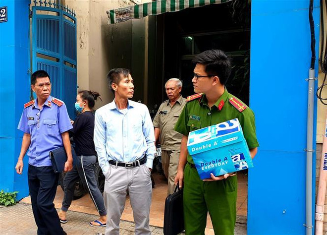 Cơ quan chức năng dẫn giải những người liên quan đi sau khi thực hiện việc khám xét Công ty PIT Travel. (Ảnh: TTXVN phát) Bắt tạm giam Giám đốc, kế toán Công ty PIT Travel liên quan đến SAGRI ảnh 1
