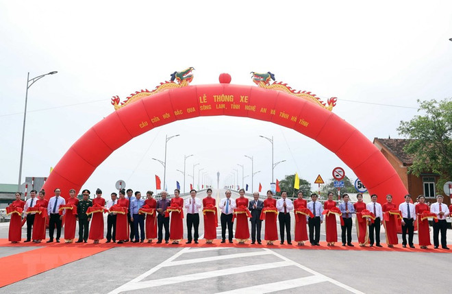Thủ tướng Nguyễn Xuân Phúc và các đại biểu thực nghiện nghi thức cắt băng thông xe cầu Cửa Hội bắc qua Sông Lam. (Ảnh: Thống Nhất/TTXVN) Thông xe cầu Cửa Hội bắc qua Sông Lam nối tỉnh Nghệ An và Hà Tĩnh ảnh 1