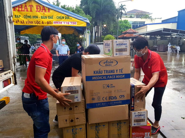 Đại diện Ban Quản lý các Khu chế xuất, Khu công nghiệp thành phố cùng Hiệp hội doanh nghiệp thành phố tặng quà cho công nhân đang cách ly trong Công ty thực phẩm Vạn Đức, Khu công nghiệp Vĩnh Lộc. (Ảnh: TTXVN phát) Phong tỏa 6 xí nghiệp, nhà máy, xưởng may ở TP.HCM để chống dịch ảnh 1