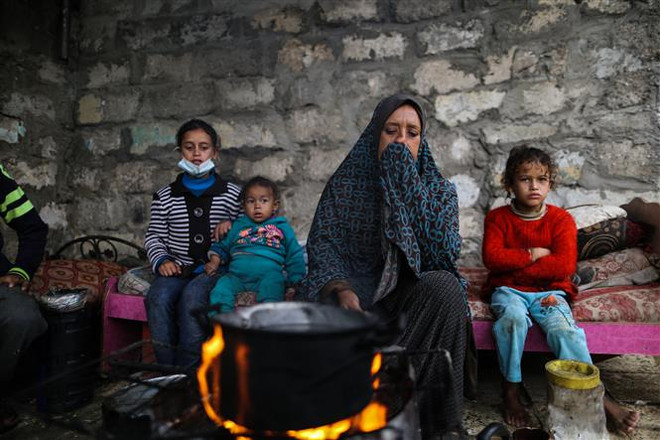 Người dân Palestine sưởi ấm tại trại tị nạn ở thành phố Khan Younis, Dải Gaza. (Ảnh: THX/TTXVN) Sứ mệnh của Liên hợp quốc và 4 mục tiêu chưa thể hoàn thành ảnh 2