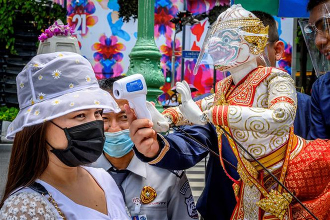 Đo thân nhiệt cho khách thăm quan phòng lây nhiễm COVID-19 tại một ngôi đền ở Bangkok, Thái Lan. (Ảnh: AFP/TTXVN) Thái Lan đón du khách quốc tế sau 7 tháng đóng cửa biên giới ảnh 1