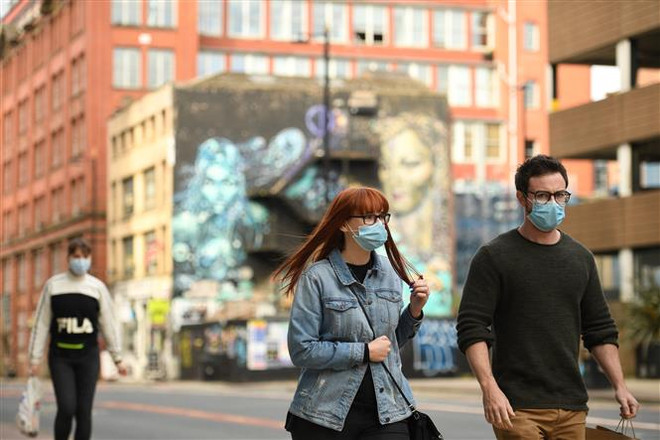Người dân đeo khẩu trang phòng lây nhiễm COVID-19 tại Manchester, Anh. (Ảnh: AFP/TTXVN) Hàng triệu người dân châu Âu phải chịu cảnh phong tỏa do COVID-19 ảnh 3