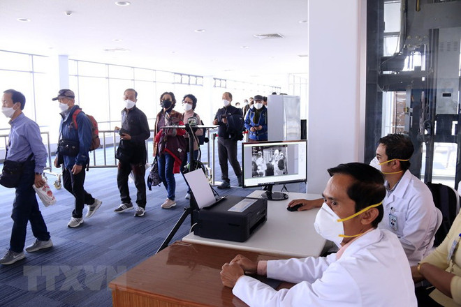 Hành khách đến Lào qua các cửa khẩu quốc tế sẽ được kiểm tra thân nhiệt, sau đó sẽ được yêu cầu sát khuẩn tay trước khi nhập cảnh Lào. (Ảnh: Phạm Kiên/Vietnam+) Lào tăng cường phòng chống dịch, chuẩn bị các hội nghị cấp cao khu vực ảnh 1