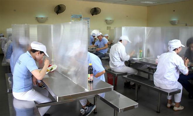 Các công nhân được bố trí ngồi ăn giãn cách, có vách ngăn. (Ảnh: TTXVN) Đẩy mạnh khai báo y tế, tiếp tục truy vết, cách ly các trường hợp F1 ảnh 2