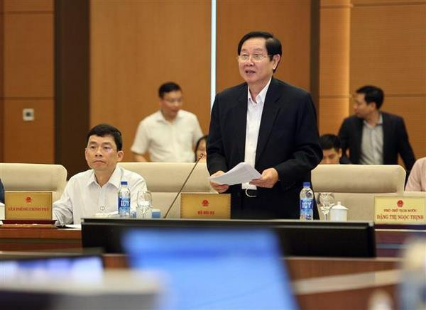 Bộ trưởng Bộ Nội vụ Lê Vĩnh Tân trình bày Tờ trình. (Ảnh: Dương Giang/TTXVN) Làm rõ việc xóa tư cách chức vụ đối với cán bộ, viên chức nghỉ hưu ảnh 3