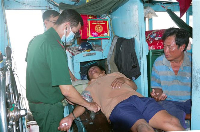 Quân y Bộ đội Biên phòng Sóc Trăng thăm khám sức khoẻ ban đầu cho 2 ngư dân gặp nạn. (Ảnh: Trung Hiếu/TTXVN) Bộ đội Biên phòng Sóc Trăng tiếp nhận 2 thuyền viên gặp nạn trên biển ảnh 1