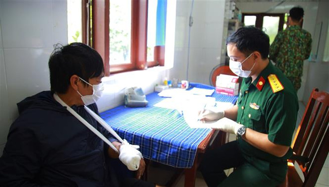 Cán bộ quân y thăm khám, kiểm tra sức khỏe cho bệnh nhân Mai Văn Miên (bên trái). (Ảnh: TTXVN phát) Trung tâm y tế thị trấn Trường Sa cấp cứu ngư dân gặp nạn trên biển ảnh 1