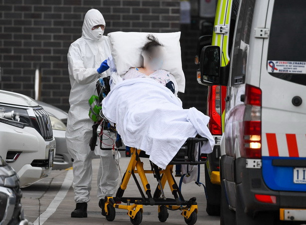 Nhân viên y tế chuyển bệnh nhân COVID-19 lên xe cứu thương tại thành phố Melbourne, Australia. (Ảnh: AFP/TTXVN) Australia: Bé gái chịu ảnh hưởng của COVID-19 nghiêm trọng hơn bé trai ảnh 1