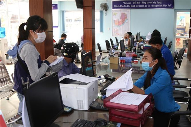 Cán bộ UBND phường Hiệp Bình Chánh, thành phố Thủ Đức, hướng dẫn thủ tục hành chính cho người dân. (Ảnh: Xuân Tình/TTXVN) TPHCM thay đổi phương thức làm việc, tuân thủ giãn cách xã hội ảnh 1