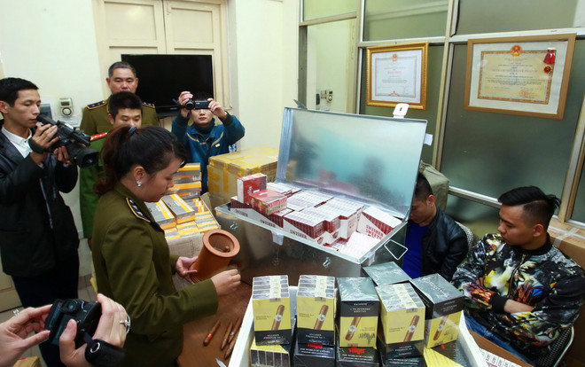 Lực lượng chức năng kiểm tra hàng nhập lậu tại cơ quan công an. (Ảnh: Doãn Tấn/TTXVN) Hà Nội bắt vụ vận chuyển lượng lớn thuốc lá, xì gà nhập lậu ảnh 1
