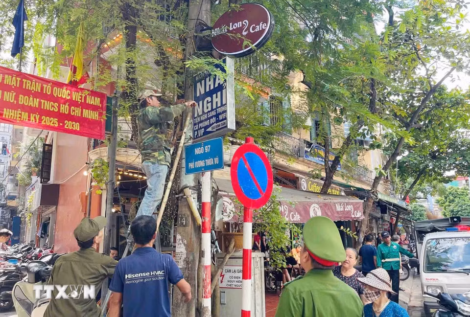 Lực lượng chức năng phường Phương Liệt tổ chức tháo dỡ biển quảng cáo đặt sai quy định tại ngõ 97 phố Vương Thừa Vũ (khu vực giáp ranh giữa hai phường). (Ảnh: Phạm Kiên/TTXVN)