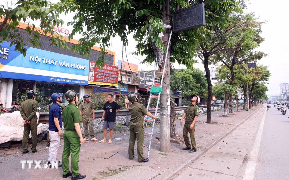 Tổ công tác của phường Phương Liệt tổ chức tháo dỡ các biển quảng cáo đặt sai quy định tại tuyến đường Giải Phóng.(Ảnh: Phạm Kiên/TTXVN)