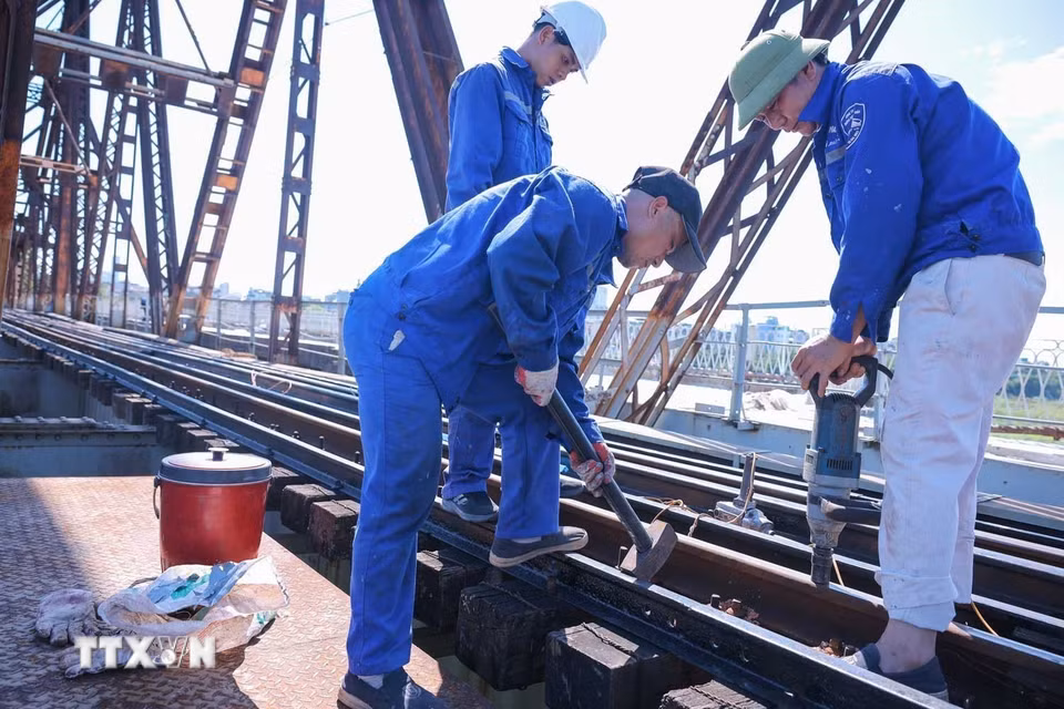 Công nhân đang triển khai bảo dưỡng hệ thống đường sắt trên cầu Long Biên giữa trưa nắng tới 40 độ. (Ảnh: Hoàng Hiếu/TTXVN)
