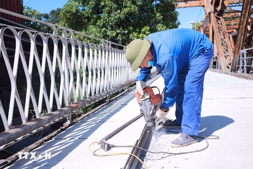 Giữa trưa 24/5, các công nhân vẫn khẩn trương hoàn thiện những công đoạn cuối trên mặt đường cầu Long Biên. (Ảnh: Hoàng Hiếu/TTXVN)
