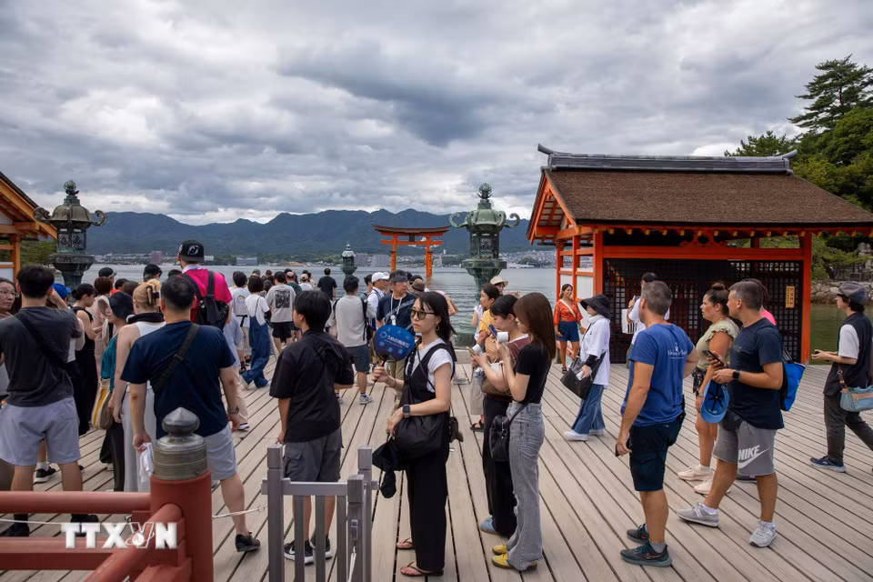 Du khách xếp hàng để chụp ảnh lưu niệm cùng cánh cổng Torii. (Ảnh: Xuân Giao/TTXVN)
