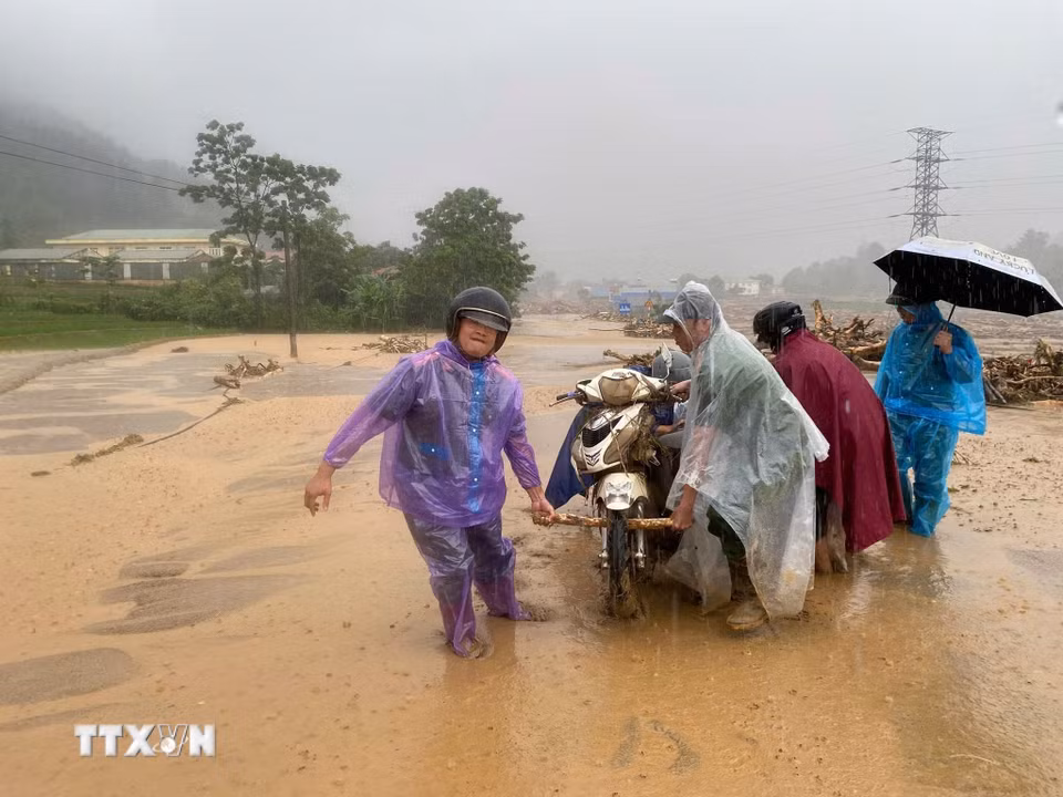 Người dân lội bùn di dời xe máy tại điểm sạt lở ở xã Mường Than, Lai Châu. (Ảnh: TTXVN phát)