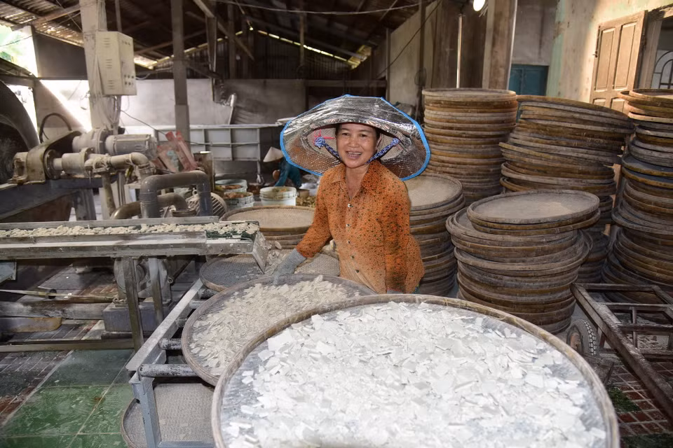 Chị Huỳnh Thị Hồng Nga hứng bột vào nia, dàn đều rồi đem phơi nắng. (Ảnh: Đức Hạnh/TTXVN)
