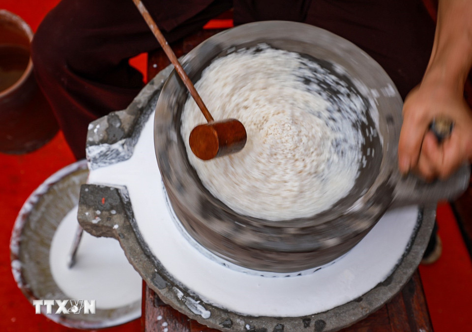 Công đoạn xay gạo bằng cối đá truyền thống. (Ảnh: Khánh Hòa/TTXVN)