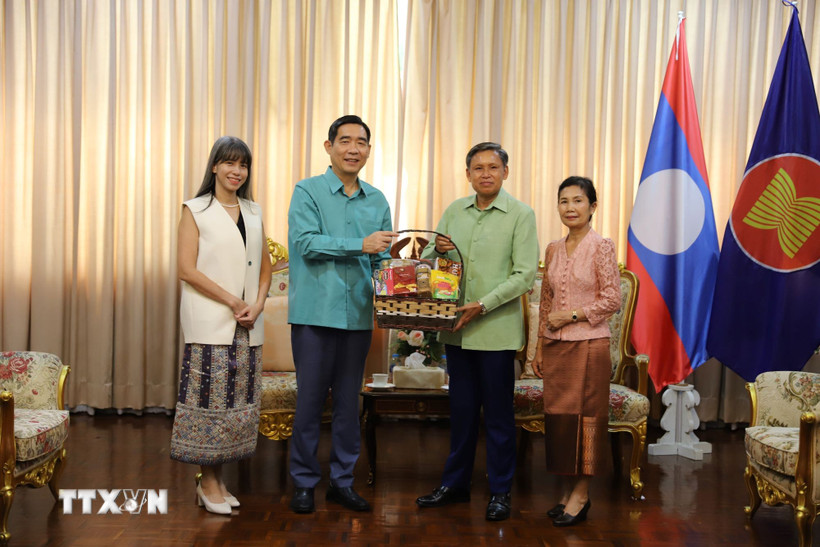 Đại sứ Phạm Việt Hùng (trái) và phu nhân trao lẵng quà tặng Đại sứ Lào Sisavath Inphachanh và phu nhân. (Ảnh: Đỗ Sinh/TTXVN)