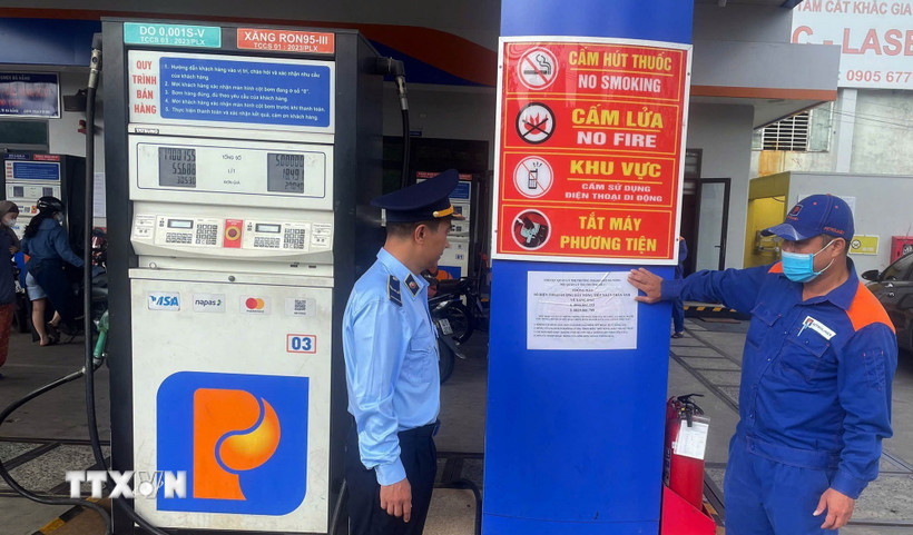 Lực lượng quản lý thị trường thành phố Đà Nẵng triển khai dán thông báo số điện thoại đường dây nóng, tại các cửa hàng xăng, dầu. (Ảnh: Trần Tĩnh/TTXVN)