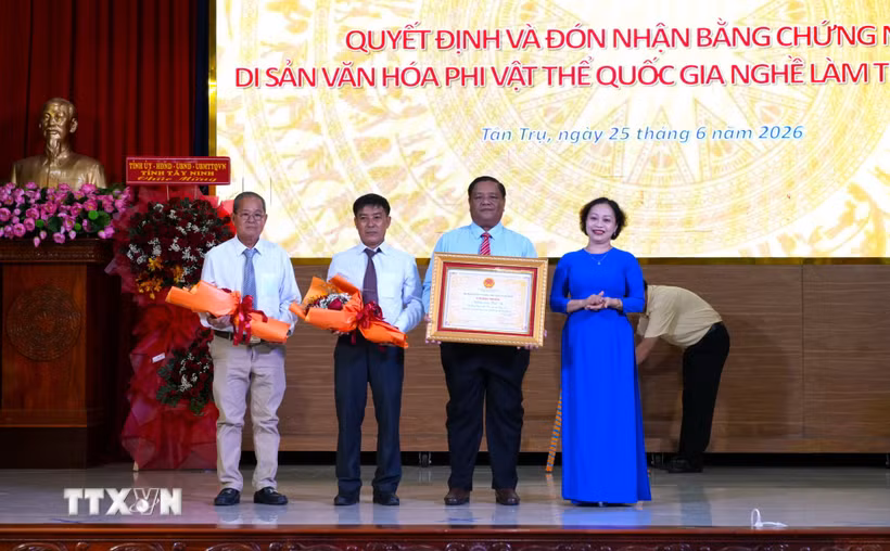 Bà Trần Thị Đoan Quang, Giám đốc Bảo tàng tỉnh Tây Ninh trao Bằng chứng nhận Di sản Văn hóa Phi vật thể Quốc gia đối với Nghề làm trống Bình An cho lãnh đạo Ủy ban Nhân dân xã Tân Trụ. (Ảnh: Thanh Bình/TTXVN)