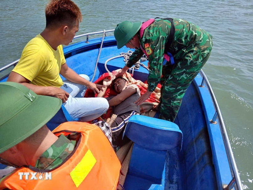 Chiến sỹ Đồn Biên phòng Ngọc Vừng hỗ trợ đưa ngư dân gặp nạn sang tàu khác an toàn. (Ảnh: TTXVN phát)