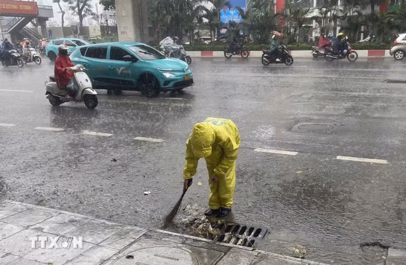 Công nhân Công ty Trách nhiệm hữu hạn Một thành viên Thoát nước Hà Nội vớt rác để tiêu thoát nước nhanh khi mưa lớn. (Ảnh: Nguyễn Thắng/TTXVN)