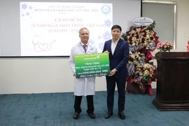 Đồng chí Hồng Quang - Thành viên Hội đồng quản trị, Chủ tịch Công đoàn Vietcombank (bên phải) trao biển tượng trưng hỗ trợ 500 triệu đồng cho Bệnh viện Đa khoa Khu vực Hóc Môn. (Ảnh: Vietnam+) 